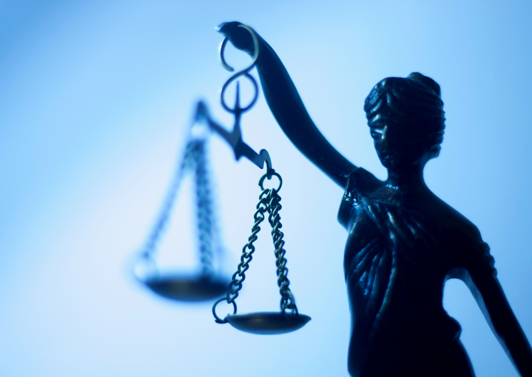 Bronzefigur der Justitia mit Waage vor blauem Hintergrund als Symbol für Teilnahmebedingungen